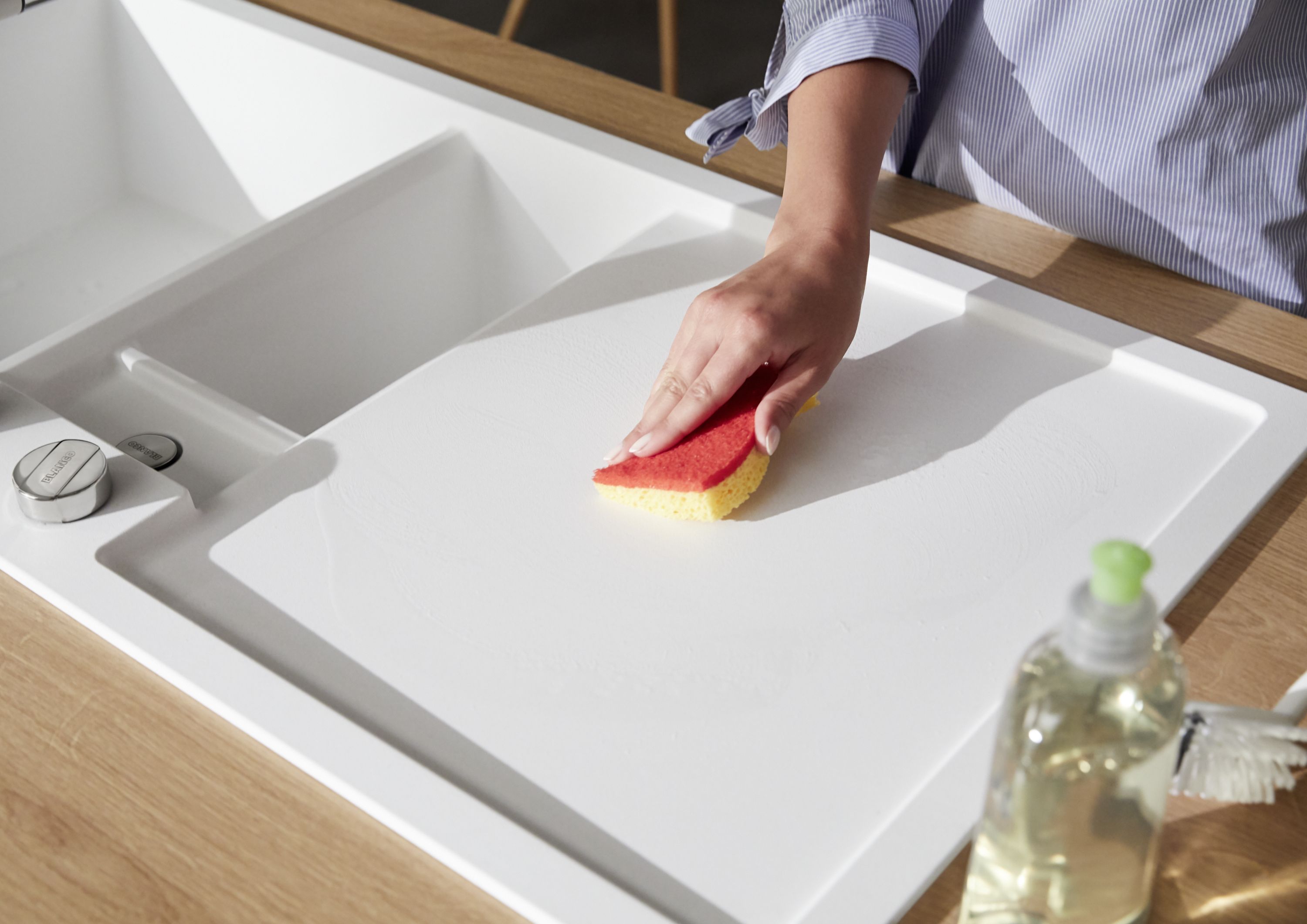 A Silgranit sink is cleaned with a sponge