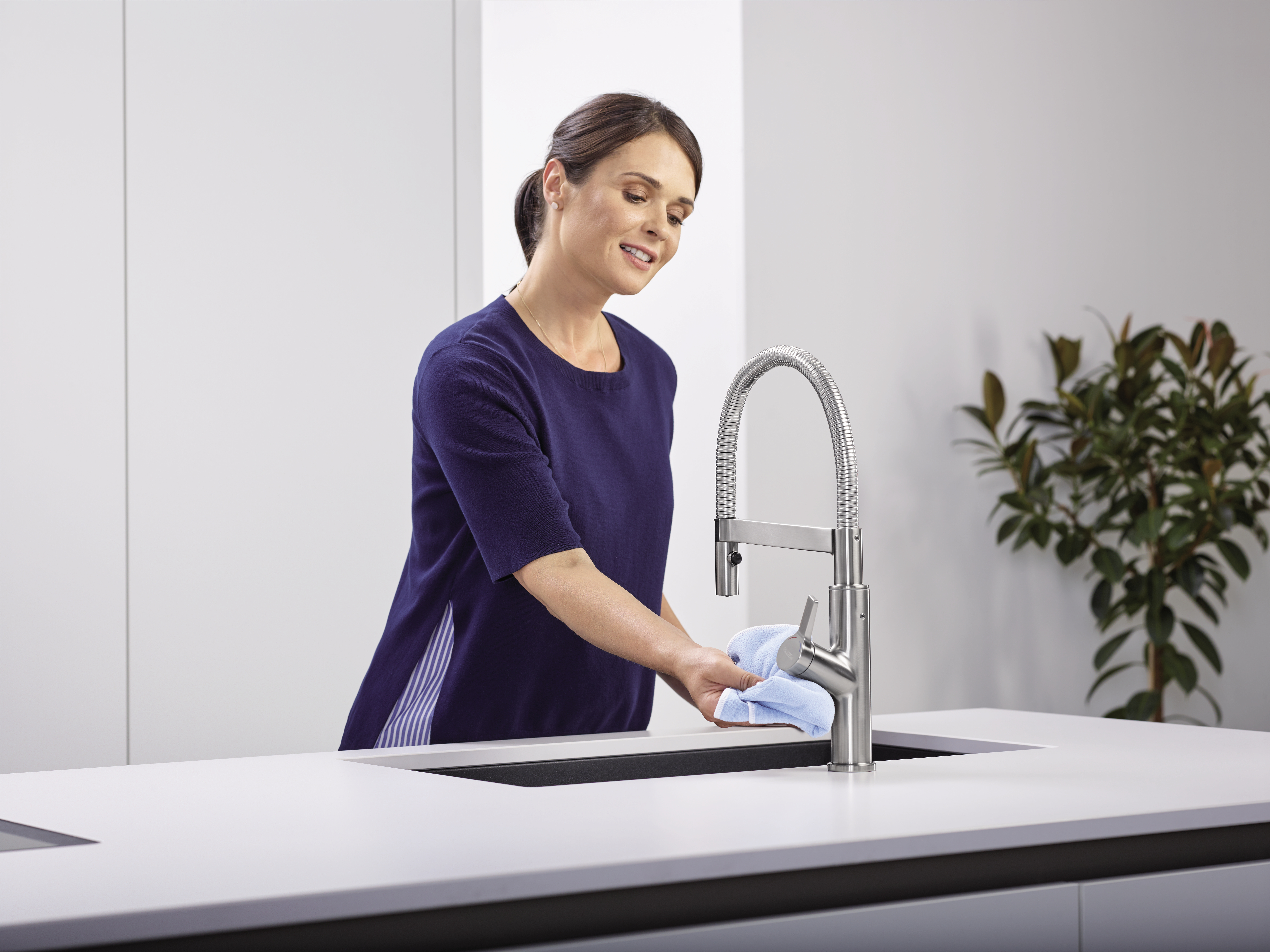 A housewife cleans the mixer tap with a microfibre cloth