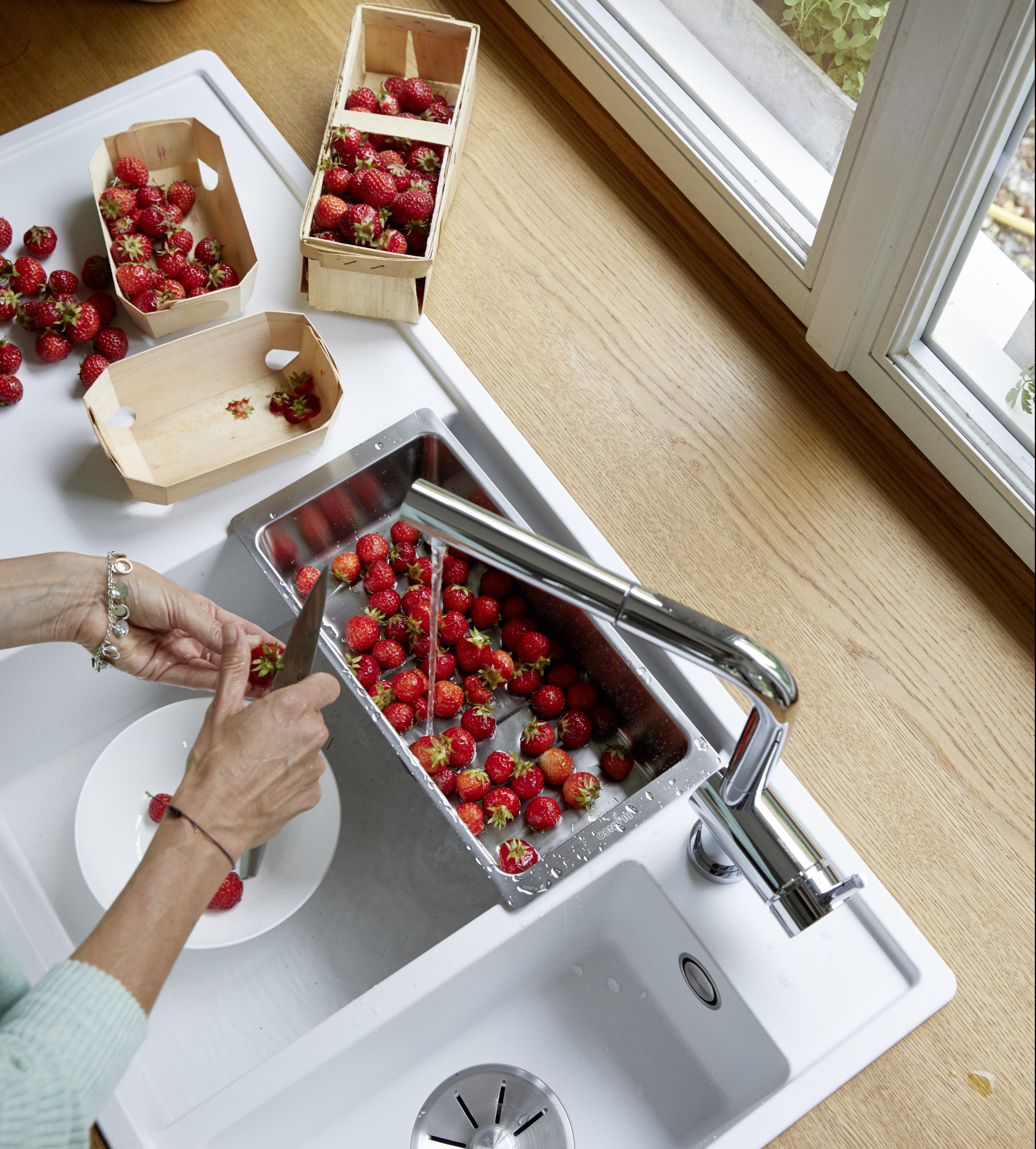 a woman cuts strawberries over a BLANCO sink