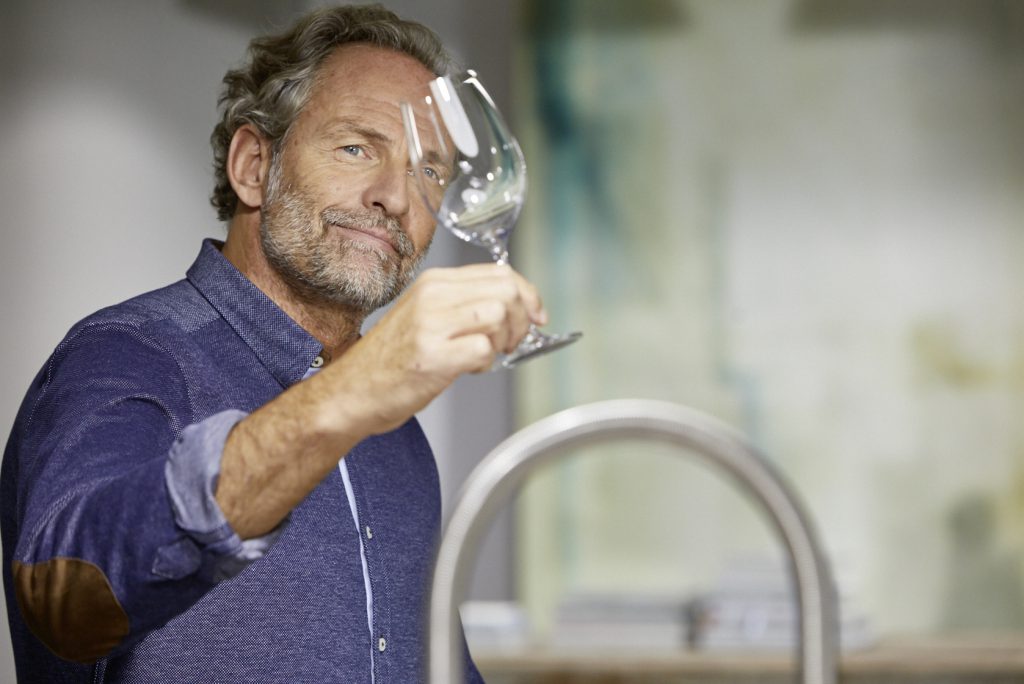 A man looks at a perfectly polished wine glass